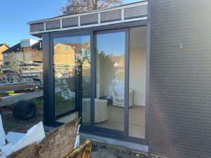 Aanbouw in Brakel met donkere aluminium schuifpuien over de volle gevelbreedte