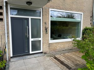 Antracieten kunststof voordeur met zijlicht naast een breed raam